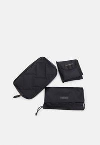 Svart accessoarset som inkluderar en vadderad påse, en hopfälld skötmatta och en tvättpåse, alla med eleganta designer och minimal varumärkesprofil.