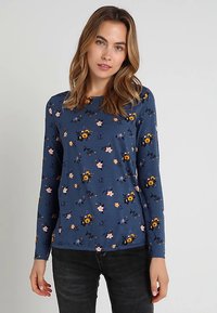 Langärmliges blaues Hemd mit einem Blumenmuster in Gelb, Pink und Grün. Hergestellt aus weichem Stoff, mit rundem Halsausschnitt und schlanker Passform.