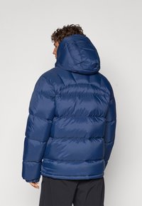 Blue puffer jacket with a hood. Features quilted sections and a smooth, shiny texture. Includes adjustable cuffs and a relaxed fit.