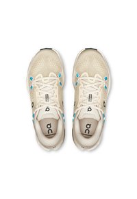Scarpe da ginnastica beige con tomaia in rete, accenti blu e suole bianche. Presentano lacci, logo sulla linguetta e colli imbottiti per il comfort.