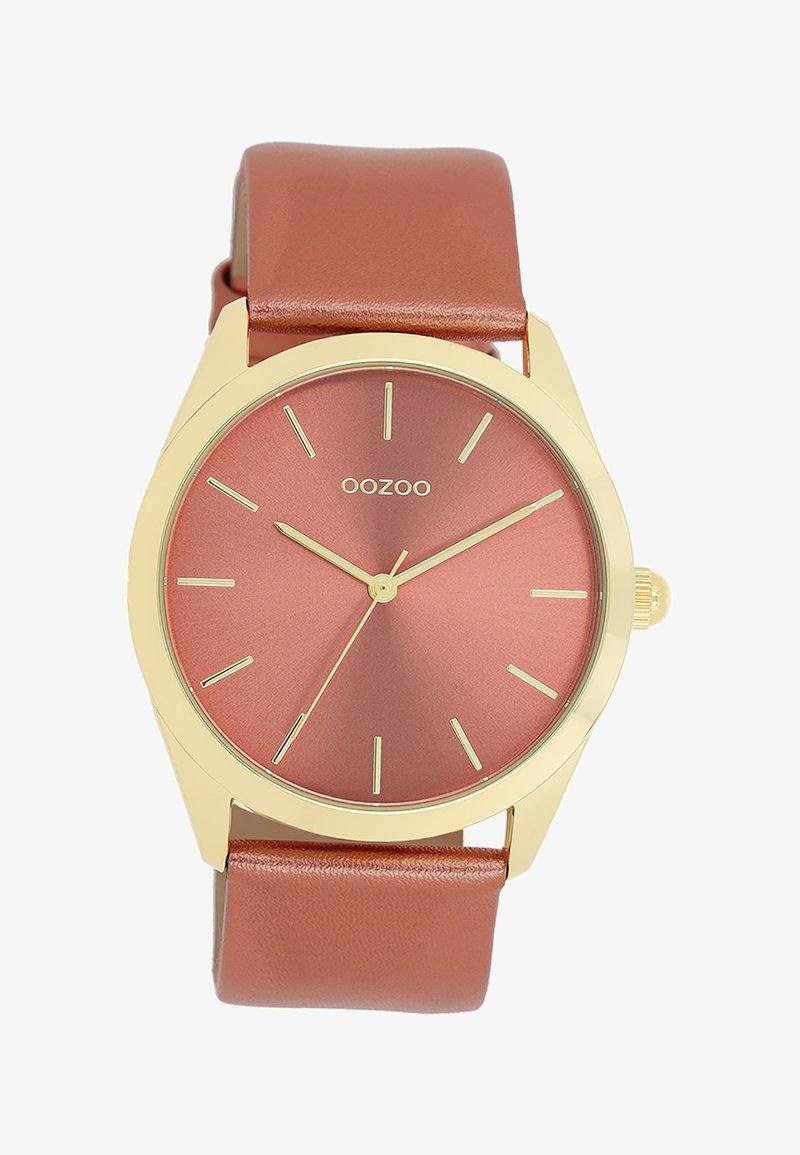 Montre-bracelet ronde avec boîtier en or, cadran couleur rouille, index et aiguilles dorés, et bracelet en cuir marron assorti.