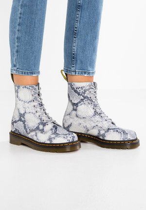 Šedé a bílé kožené ankle boots s hadím vzorem, kulatou špičkou, šněrováním a žlutým akcentem na patě, na tmavé gumové podrážce.