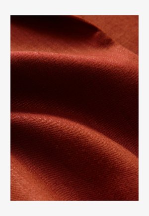 Rostfarbener Stoff mit glatter Textur, der sanfte Falten und ein leicht grobes Webmuster zeigt.