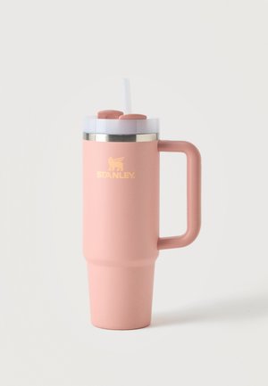Gobelet de voyage en acier rose mat avec poignée, couvercle transparent, paille et logo Stanley doré à l'avant sur un fond clair uni.