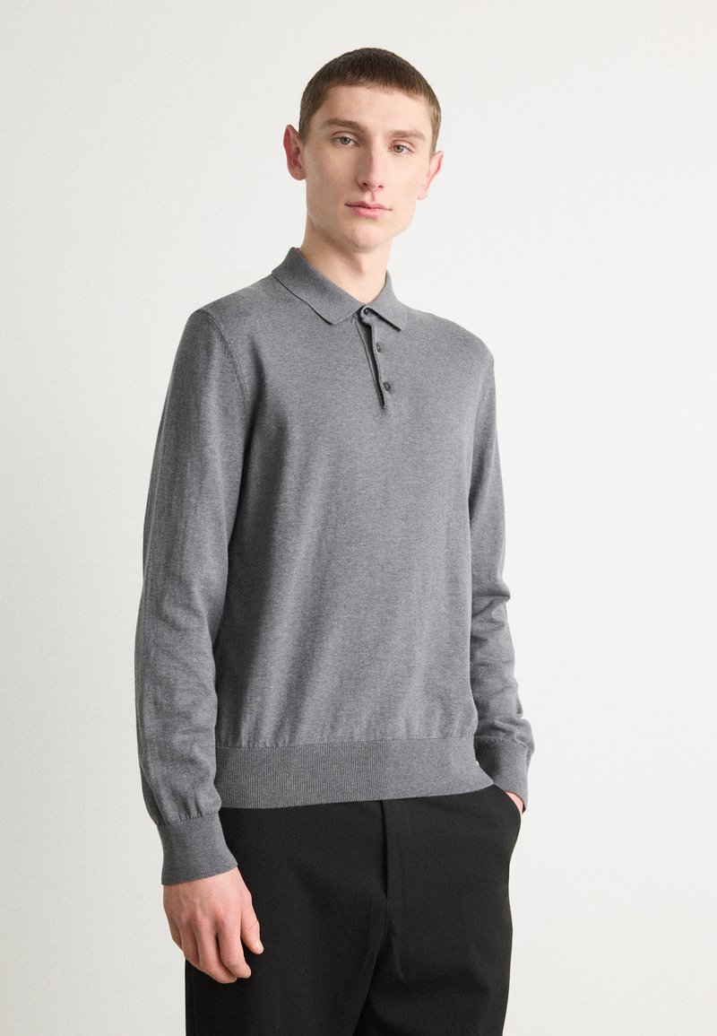 Polo shirt grigio a maniche lunghe con colletto, patta con tre bottoni e polsini a coste. Tessuto liscio e design aderente.
