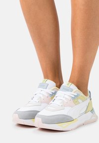 Vita sneakers med grå, rosa och gula accenter. Har en design i blandade material, vadderad plös och strukturerad sula för bra grepp.