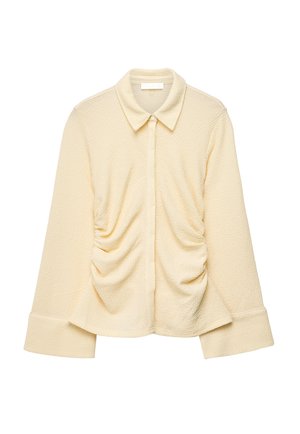 Kreemjas tekstuuriga pika varrukaga pluus laiade mansettide, kogutud külgedega, terava krae ja peidetud ees nööbiliistuga.