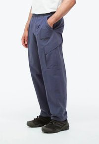 Pantalones cargo de tejido azul oscuro con cintura elástica, bolsillos laterales y un corte casual. Presenta un logo de la marca en la parte frontal.