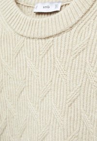 Maglione lavorato a maglia beige con un collo a girocollo a coste e un motivo zigzag testurizzato su tutta la superficie. Etichetta visibile all'interno.