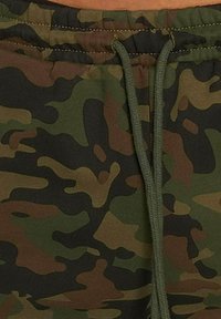 Pantaloni tuta mimetici con una combinazione di modelli verdi, marroni e neri, caratterizzati da una vita con cordoncino e un tessuto morbido e testurizzato.