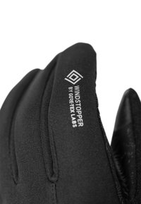 Schwarze Handschuhe mit passgenauer Gestaltung und dem Branding "WINDSTOPPER von GORE-TEX LABS". Glatte Textur, verstärkte Nähte und gebogene Fingerspitzen.