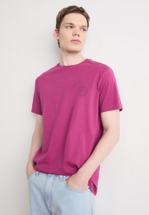 Magenta Kurzarm-T-Shirt aus Baumwollmaterial mit rundem Ausschnitt und kreisförmigem Logodetail auf der linken Brustseite. Lässige Passform.
