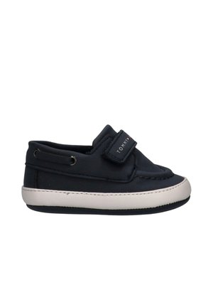 Scarpa per bambino in blu navy con suola bianca, cinturino in Velcro con etichetta "Tommy" e cuciture in stile mocassino su sfondo bianco.