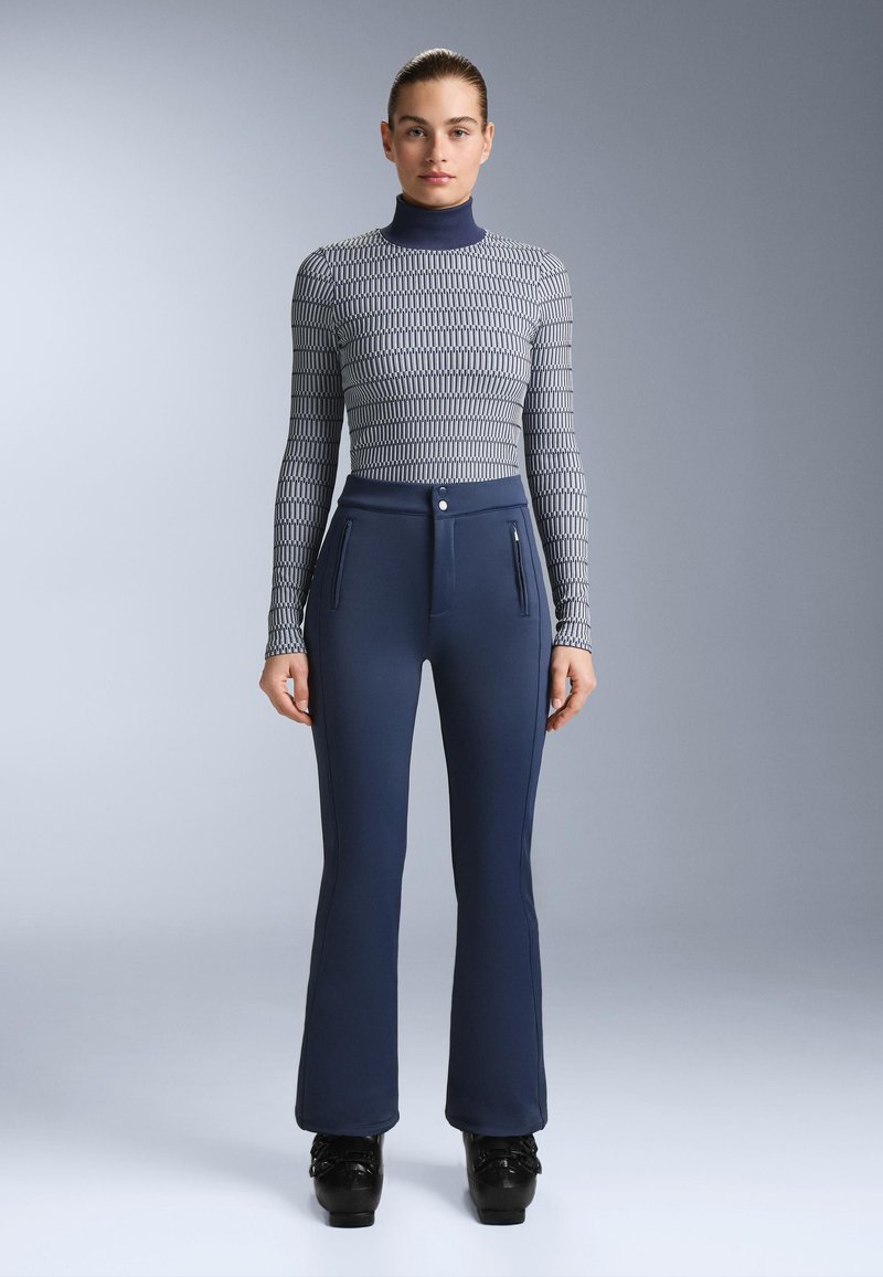 Dopasowana bluzka z długim rękawem w szarym wzorzystym materiale, z golfem. Granatowe rozkloszowane spodnie z przednimi kieszeniami na zamek i gładką fakturą.