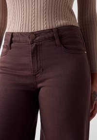 Jeans in denim marrone a vita alta con una texture liscia, dotati di tasche frontali e chiusura con bottone in metallo.