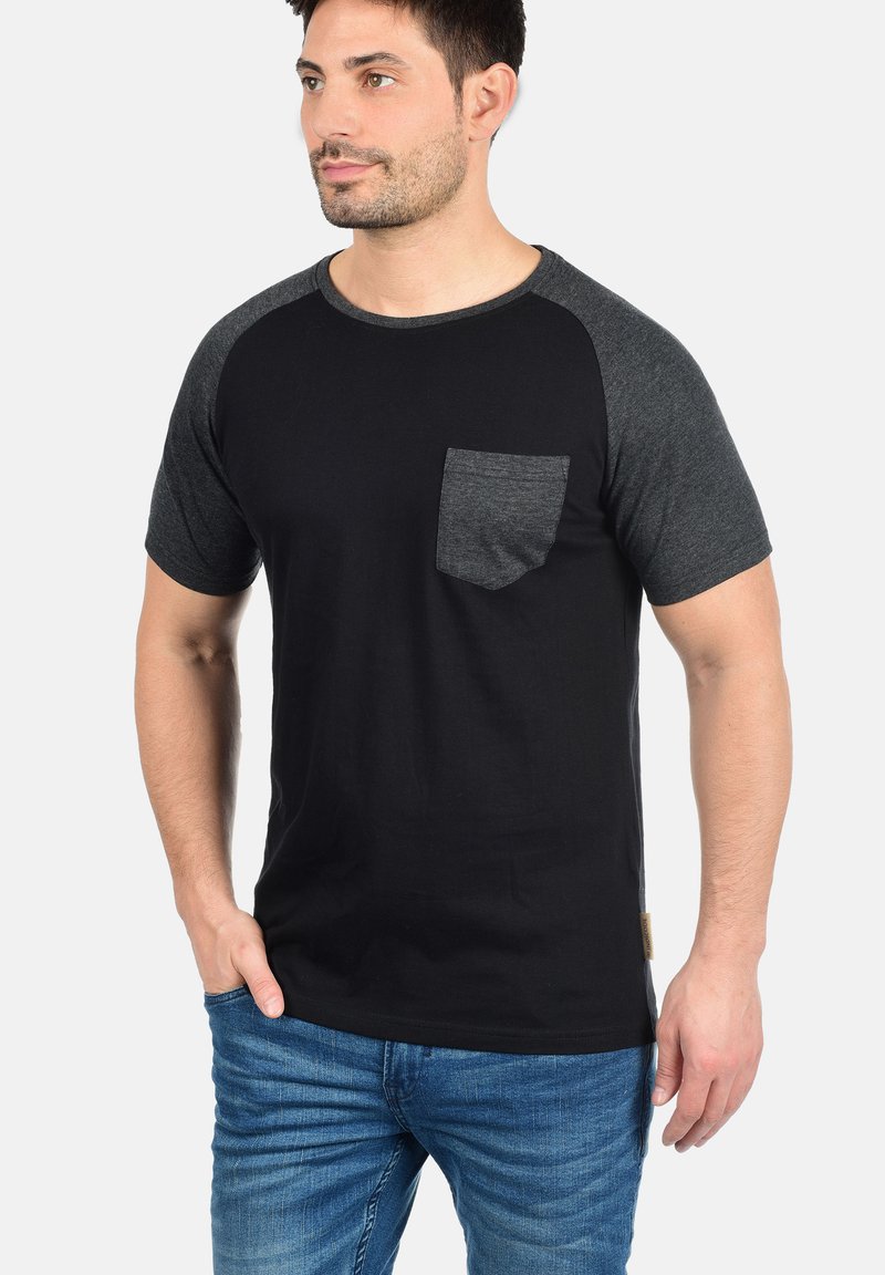 Black T-shirt with dark gray raglan sleeves and a chest pocket. Made of cotton, features a smooth texture and subtle stitching details.