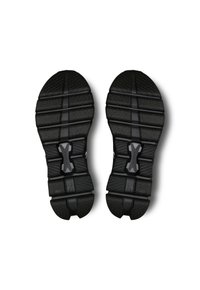 Semelle de chaussure de sport noire en caoutchouc, présentant une surface texturée avec des motifs de crampons distincts et des éléments de rembourrage intégrés.