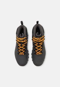 Czarne buty trekkingowe z pomarańczowymi sznurówkami, teksturowana cholewka, wyściełany kołnierz i pętla do noszenia; solidna podeszwa z wzorami zapewniającymi przyczepność.