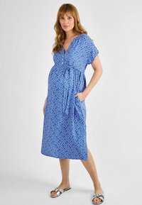 Maternity dress in a vibrant blue with white abstract pattern, featuring a v-neck, short sleeves, flowing silhouette, and side pockets.