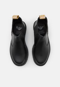 Pantofi slip-on din piele vegană neagră, cu laterale elastice și un tab de tragere galben. Au un aspect superior neted și un design texturat al talpii.