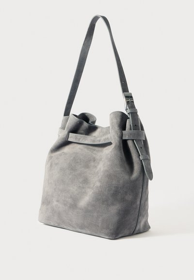 Sac à bandoulière en daim gris avec une finition douce et texturée. Présente un haut froncé, une sangle réglable et un design minimaliste.