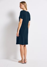 Granatowa sukienka z krótkim rękawem, dopasowana w talii i o prostym kroju. Materiał wydaje się miękki i elastyczny, z minimalnymi detalami.