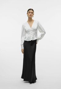 Witte satijnen blouse met een diepe V-hals en knoopsluiting, gecombineerd met een lange zwarte rok. De blouse heeft pofmouwen en een getailleerde taille.
