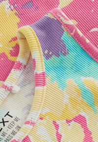 Többszínű bordázott textil, rózsaszín, sárga, lila és türkiz virágmintával, puha, texturált felülettel és varrott széllel.