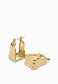 Kultaiset renkaat, joissa on aaltoileva muotoilu ja sileä, kiiltävä pinta. Niissä on käännettävä suljin turvallista käyttöä varten.