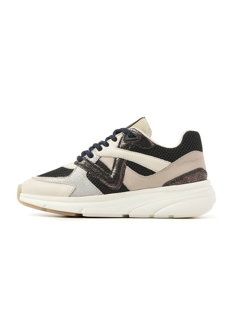 Sneaker mit einer Mischung aus Materialien: beige Leder, schwarzes Mesh und metallische Akzente. Die klobige weiße Sohle und die marineblauen Schnürsenkel runden das Design ab.