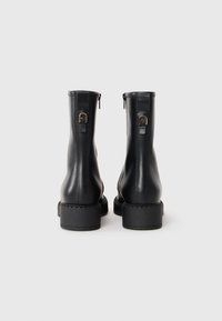 Sorte skinn ankle boots med glatt overflate, blokkhelt, og glidelåser på siden. Har en dekorativ gullaccent på helen.