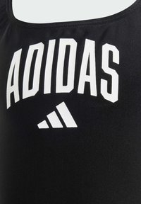 Čierny top na ramienka z hladkej tkaniny s veľkým bielym textom "ADIDAS" a logom v strede, s okrúhlym výstrihom a bez rukávov.