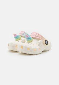 Weiße Clogs mit einer strukturierten Oberfläche, ausgestattet mit einem pinken und blauen Riemen. Die oberen Akzente umfassen einen bunten Einhornhorn und Ohren.