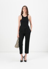 Zwarte tanktop met een aansluitend ontwerp, gecombineerd met zwarte op maat gemaakte broeken. Accessoires bestaan uit een handtas met een patroon en zwarte hoge hakken.