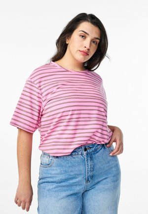 T-shirt rosa a maniche corte con strisce orizzontali marroni; vestibilità comoda e scollo rotondo, abbinata a pantaloni corti in denim azzurri a vita alta.
