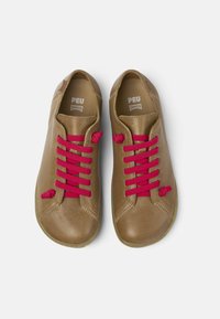 Scarpe in pelle marrone con punta arrotondata, lacci rossi e superficie strutturata. Le solette sono marchiate con "PEU CAMPER."