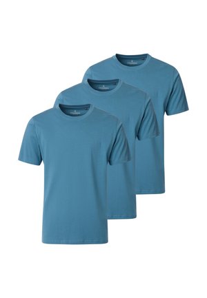 Drie effen blauwe t-shirts met korte mouwen en een ronde hals, in een over elkaar liggende, verspringende rij gelegd.