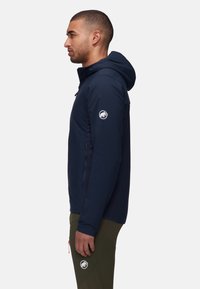 Navy blue lightweight jacket with a hood, featuring a logo on the left sleeve and a zip closure. Smooth texture and fitted design.