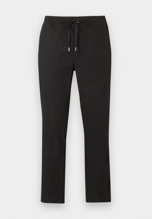 Pantalones negros de pierna recta con cinturilla elástica y cordón con puntas metálicas, extendidos sobre un fondo claro.