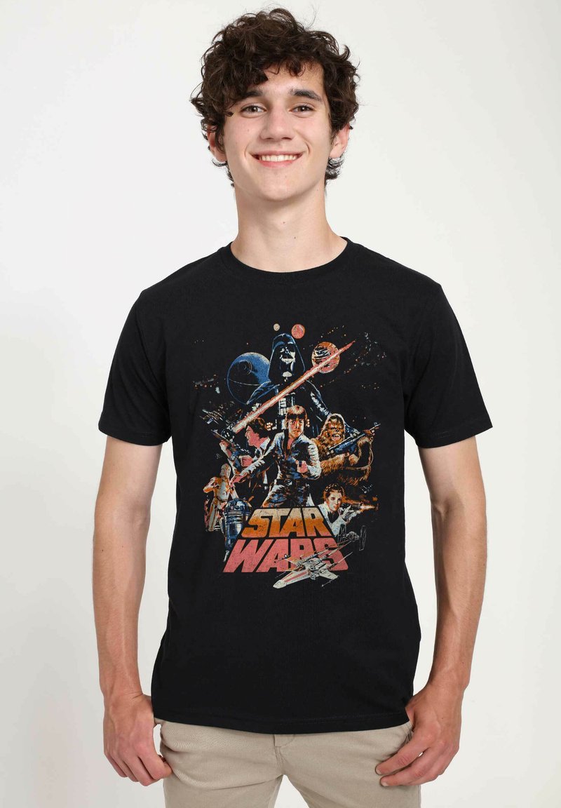 T-shirt en coton noir avec un graphique multicolore "Star Wars", représentant des personnages et des vaisseaux spatiaux dans un design rétro. Manches courtes, col rond.