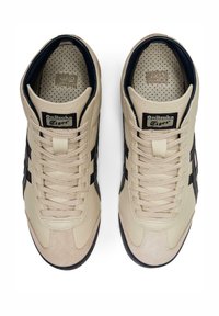 Beżowe buty sportowe z czarnymi paskami, teksturowana górna część, okrągły czubek i płaskie sznurówki. Wewnątrz znajduje się wzorzysta wkładka.