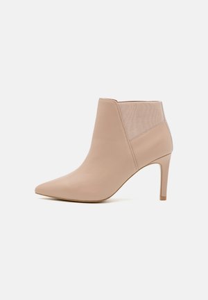 Nøgen læder ankelstøvle med spids tå, strækbare sidepaneler og høj stiletto hæl. Glat tekstur med minimale detaljer.