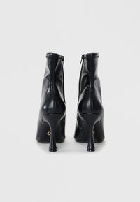 Black leather ankle boots with a high stiletto heel, featuring a zip closure at the back and a sleek design. Smooth texture and minimal detailing.