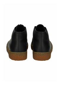 Bottes chevilles en cuir noir avec un bout rond, semelle en caoutchouc texturée et logo "CAMPER" en relief à l'arrière. Design compact et minimal.