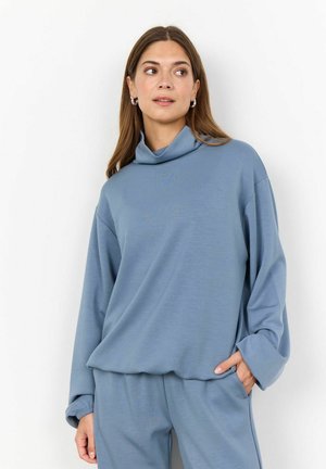 Top azzurro chiaro a maniche lunghe con colletto a dolcevita, realizzato in tessuto morbido. Presenta una vestibilità rilassata con maniche leggermente over-size e colletto ripiegato.