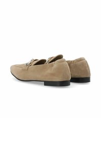 Beige suede loafers with a rounded toe, flat black heel, and decorative metal hardware. Smooth texture with stitched detailing on the upper.