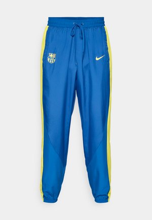 Modré športové nohavice so žltými bočnými pruhmi. Obsahujú elastický pás, šnúrku a logá futbalového tímu a Nike na prednej strane.