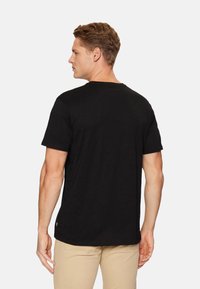 Camiseta negra de manga corta, diseño clásico de cuello redondo, tela suave, textura lisa, forma ajustada, sencilla, sin patrones ni gráficos visibles.