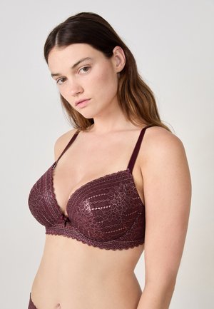 Bordeaux kanten beha met geschulpte randen, draadondersteuning en verstelbare bandjes. Bevat bloemmotieven en een decoratieve strik in het midden.