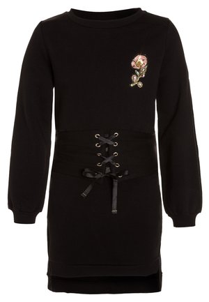 Sort kjole med lange ærmer med et pink blomstret patch på brystet og et bredt korsetlignende snørebælte i taljen.